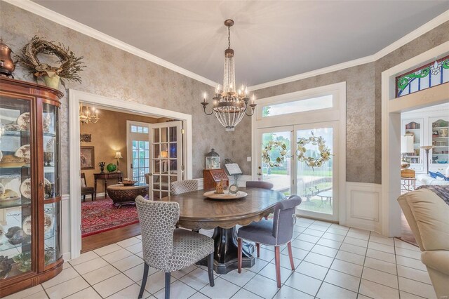 tiled dining room featuring ornamental molding, french doors, and a chandelier