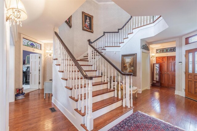 stairway featuring a high ceiling, a notable chandelier, and hardwood / wood-style flooring