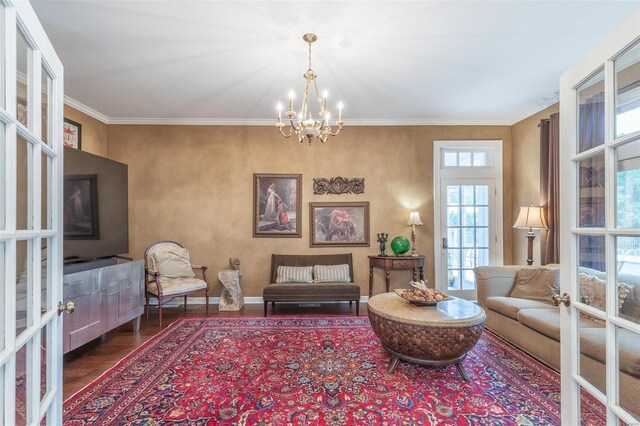 sitting room featuring hardwood / wood-style flooring, crown molding, a notable chandelier, and french doors