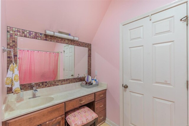 bathroom featuring lofted ceiling, a shower with shower curtain, and vanity