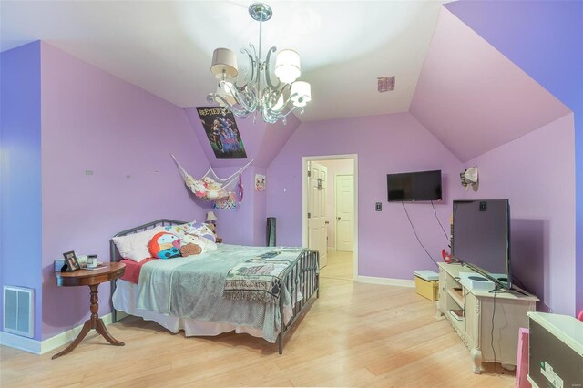 bedroom featuring a notable chandelier, light hardwood / wood-style flooring, and lofted ceiling