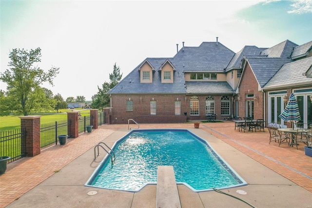 view of swimming pool with a patio area, a yard, and a diving board