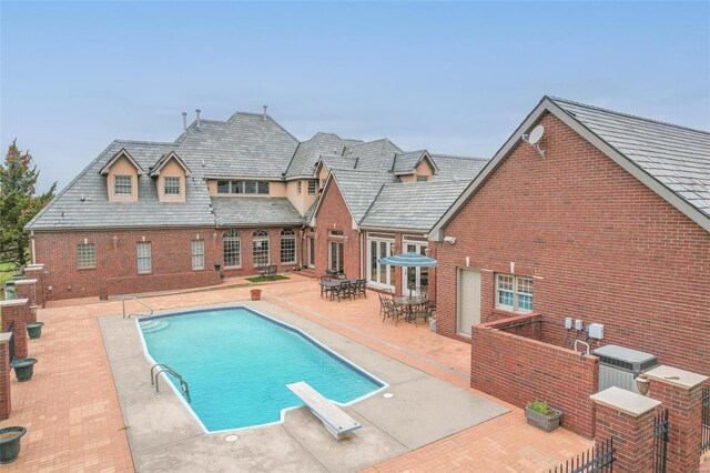 view of pool featuring a diving board and a patio