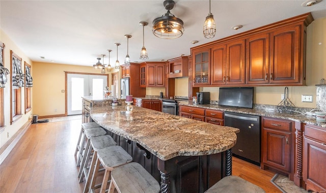 kitchen with stainless steel appliances, decorative light fixtures, light hardwood / wood-style flooring, a kitchen island, and a breakfast bar