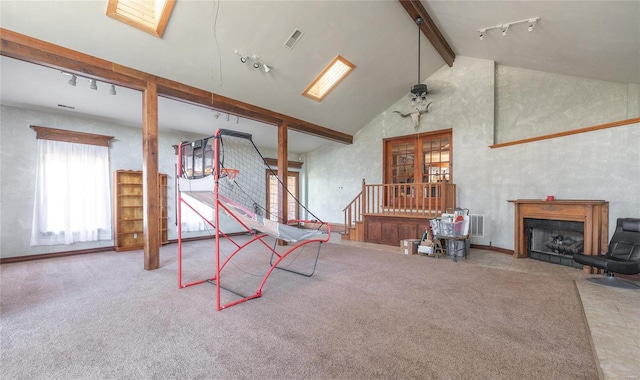 interior space featuring beam ceiling, rail lighting, a skylight, carpet floors, and high vaulted ceiling