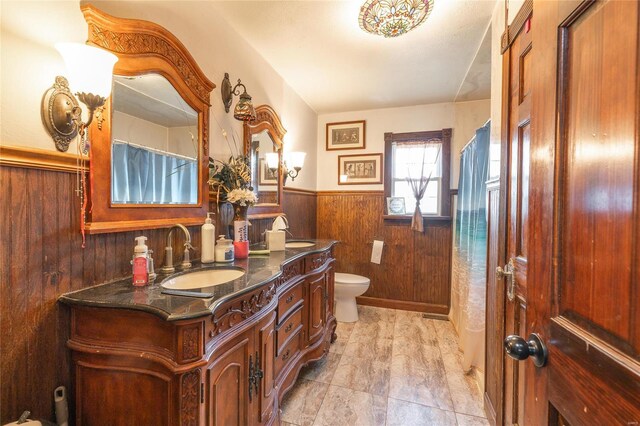 bathroom with wood walls, vanity, tile patterned floors, toilet, and a shower with curtain