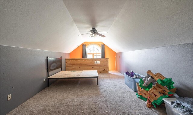 carpeted bedroom with ceiling fan, vaulted ceiling, and a textured ceiling