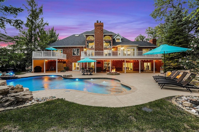 pool at dusk with a patio area and an outdoor fire pit