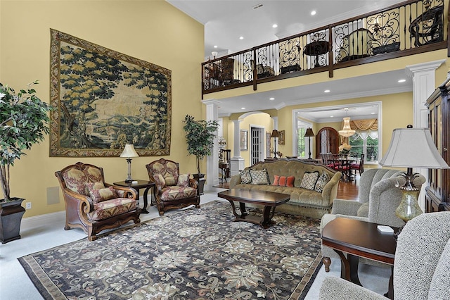 living room with ornamental molding, a high ceiling, and decorative columns