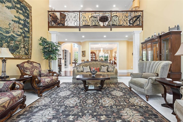 living room featuring a towering ceiling, crown molding, and decorative columns