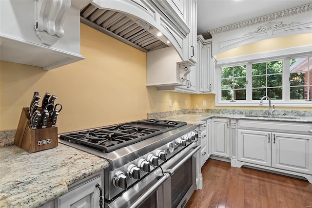 kitchen with dark hardwood / wood-style floors, custom exhaust hood, sink, range with two ovens, and white cabinets