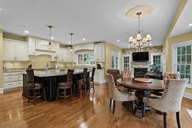 dining room featuring sink, light hardwood / wood-style floors, a fireplace, and a notable chandelier