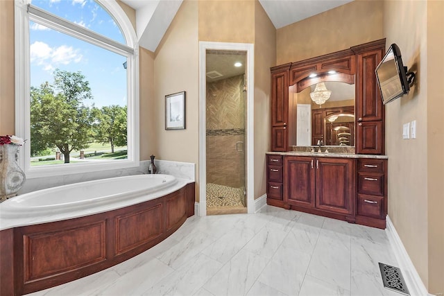 bathroom with a wealth of natural light, vanity, vaulted ceiling, and independent shower and bath