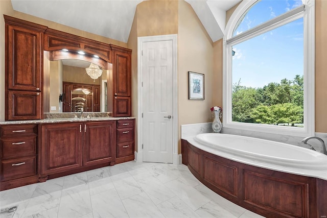 bathroom featuring a wealth of natural light, vanity, vaulted ceiling, and a bathing tub