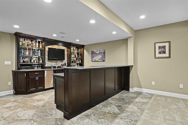 bar with stainless steel dishwasher, dark brown cabinets, and sink