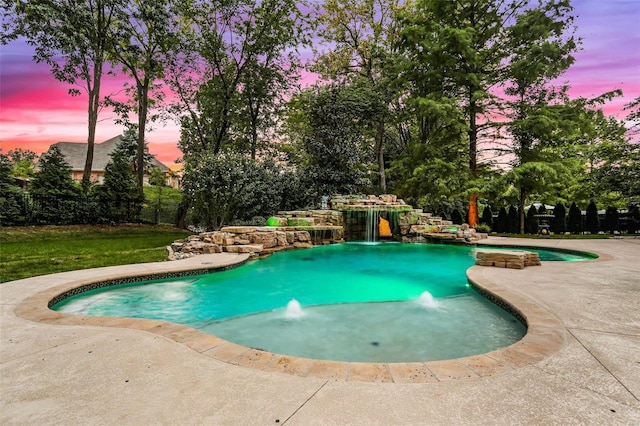 pool at dusk featuring a patio area and pool water feature