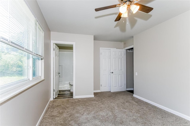 unfurnished bedroom featuring carpet floors, ceiling fan, a closet, and ensuite bath