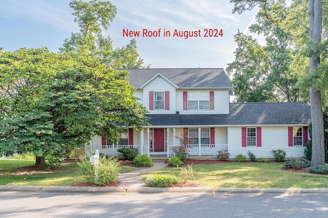 traditional home featuring a porch, a shingled roof, and a front yard