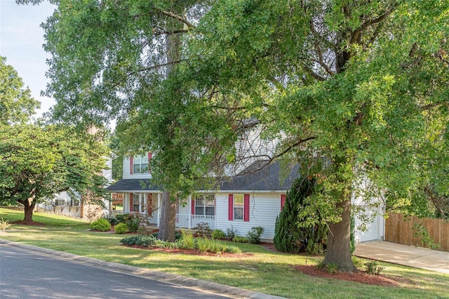 obstructed view of property with a front lawn, fence, a garage, and driveway