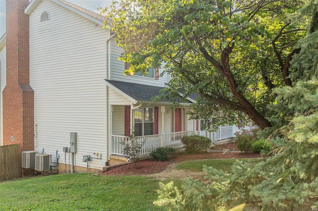 view of front of home featuring covered porch, central AC unit, a front lawn, and roof with shingles