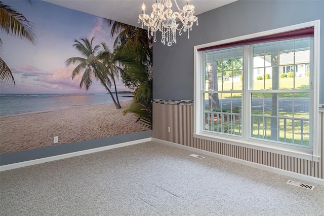 empty room featuring a wealth of natural light, visible vents, and carpet