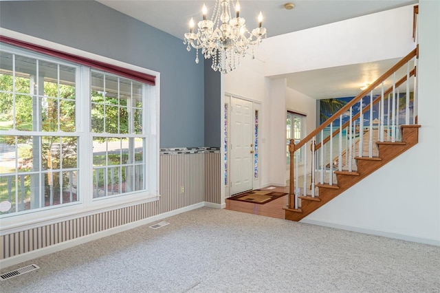 foyer featuring visible vents, carpet floors, baseboards, and stairway