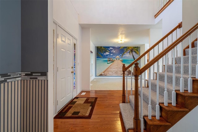 entryway with stairs, wood finished floors, baseboards, and a towering ceiling