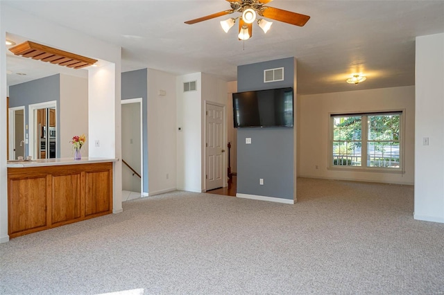 unfurnished living room with visible vents, baseboards, light colored carpet, and a ceiling fan