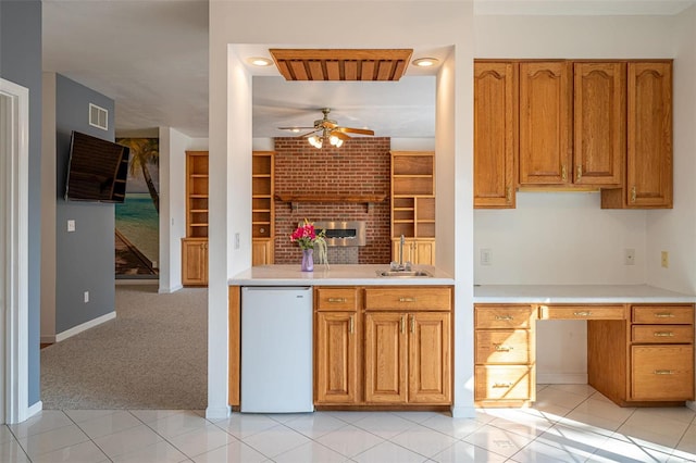 kitchen with light tile patterned floors, visible vents, a sink, fridge, and brown cabinets