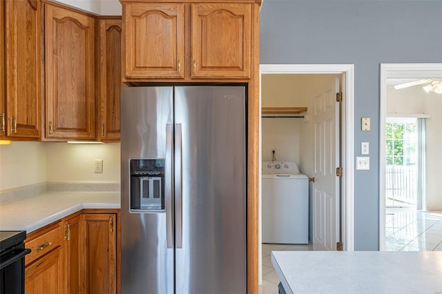 kitchen featuring stainless steel fridge with ice dispenser, light countertops, light tile patterned floors, brown cabinetry, and washer / clothes dryer