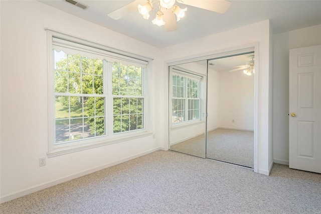 unfurnished bedroom with multiple windows, carpet floors, baseboards, and visible vents