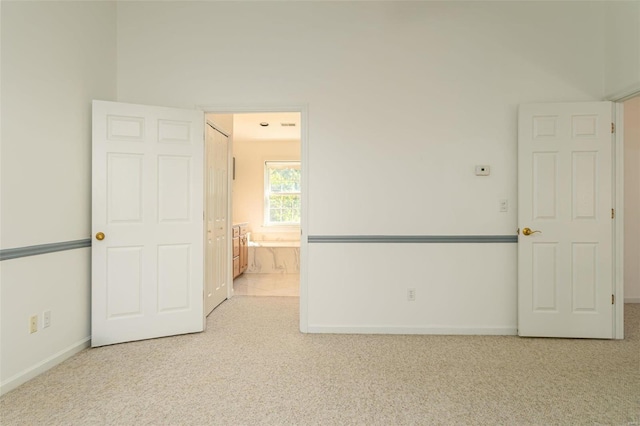 interior space featuring carpet flooring, baseboards, and connected bathroom