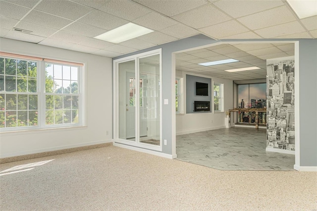 unfurnished room with carpet flooring, baseboards, visible vents, and a drop ceiling