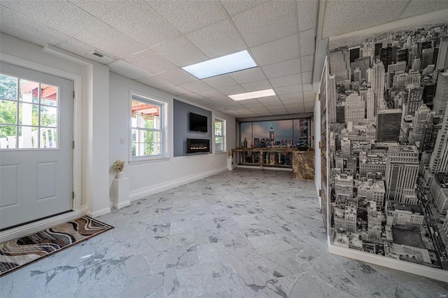 interior space with visible vents, baseboards, a drop ceiling, a fireplace, and marble finish floor