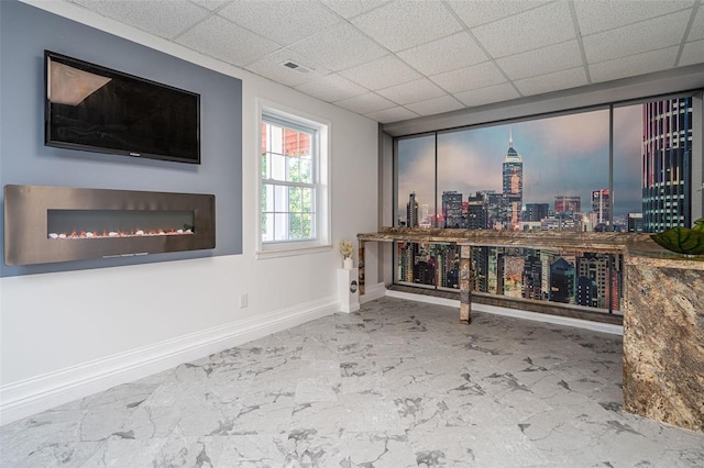 interior space with marble finish floor, visible vents, a drop ceiling, and baseboards