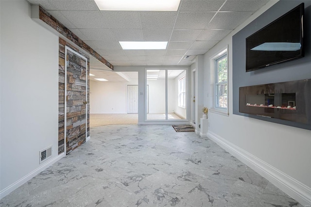 empty room featuring visible vents, a paneled ceiling, marble finish floor, and baseboards