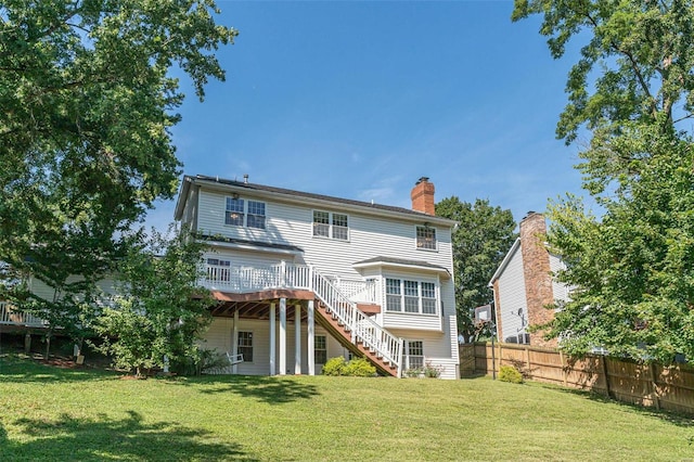 rear view of house featuring fence, a wooden deck, stairs, a chimney, and a yard