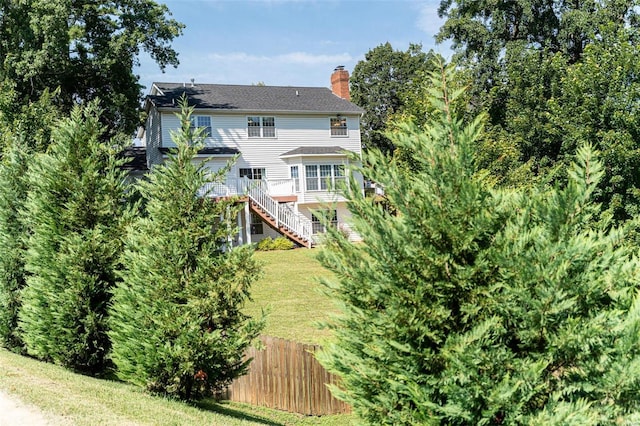 rear view of property with stairs, a yard, fence, and a chimney