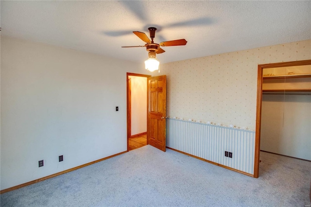 unfurnished bedroom with a closet, carpet flooring, a walk in closet, and ceiling fan