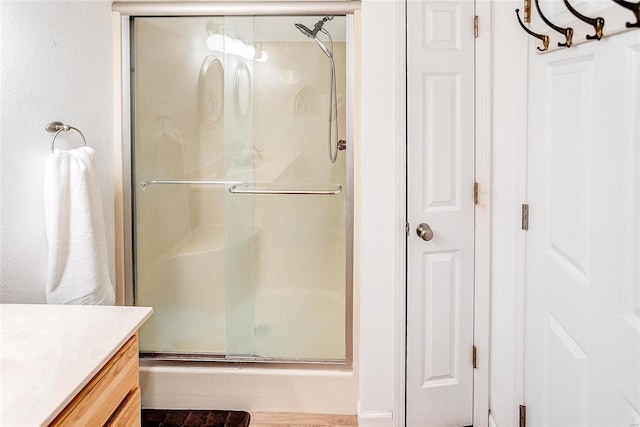 bathroom featuring a shower with door and vanity