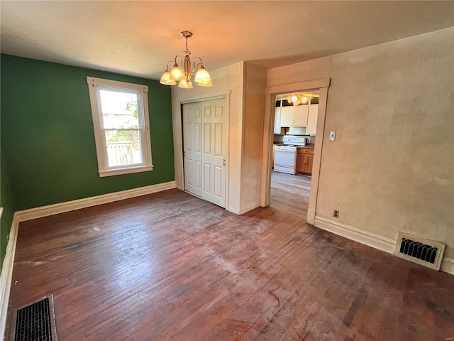 empty room with a notable chandelier and wood-type flooring