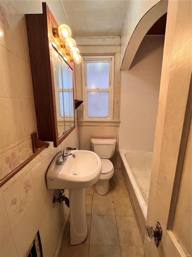 bathroom featuring tile walls, a bathtub, toilet, and tile patterned flooring