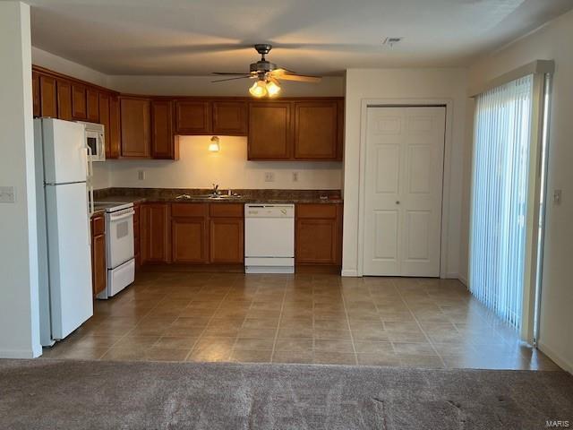 kitchen featuring ceiling fan, sink, white appliances, and light carpet