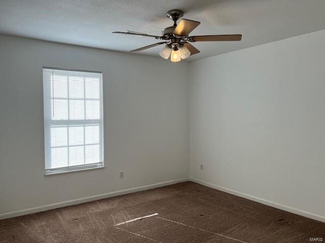 empty room featuring ceiling fan and dark carpet