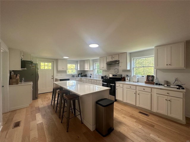 kitchen featuring light wood-type flooring, stainless steel gas range oven, and white cabinetry