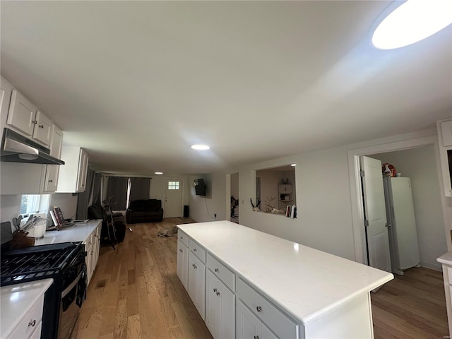 kitchen with a kitchen island, white cabinets, hardwood / wood-style floors, and black range with gas cooktop