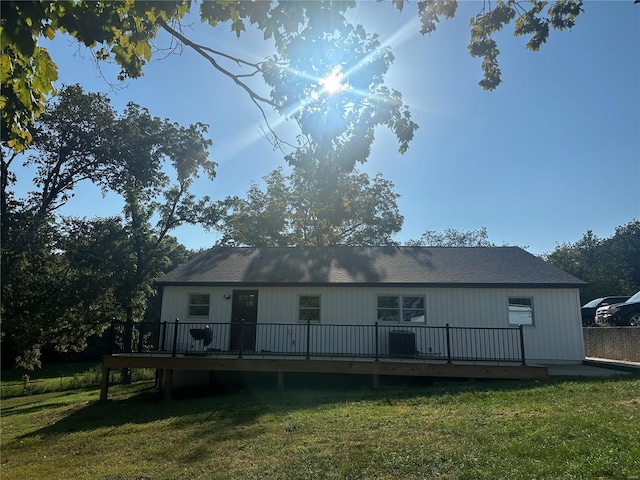 back of property with a deck and a lawn