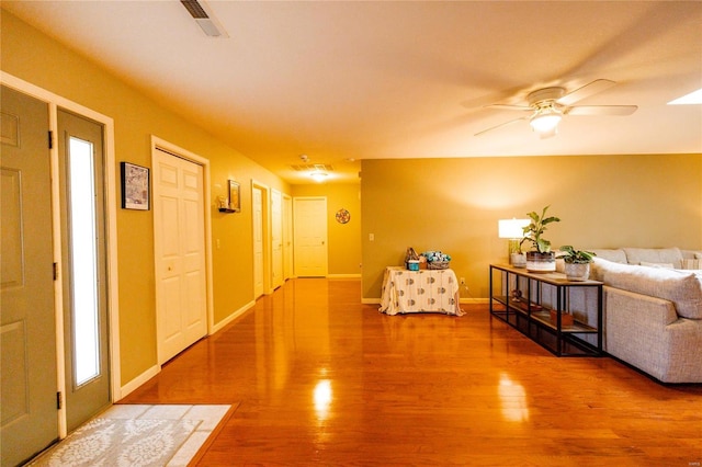 foyer with ceiling fan, visible vents, baseboards, and wood finished floors