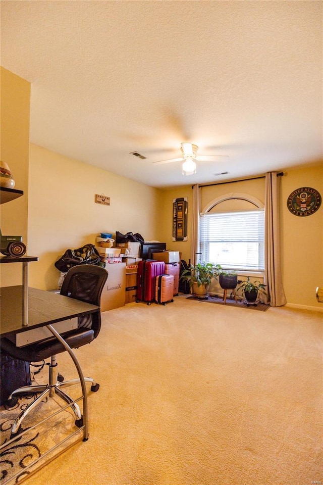 interior space with visible vents, carpet floors, a textured ceiling, and ceiling fan