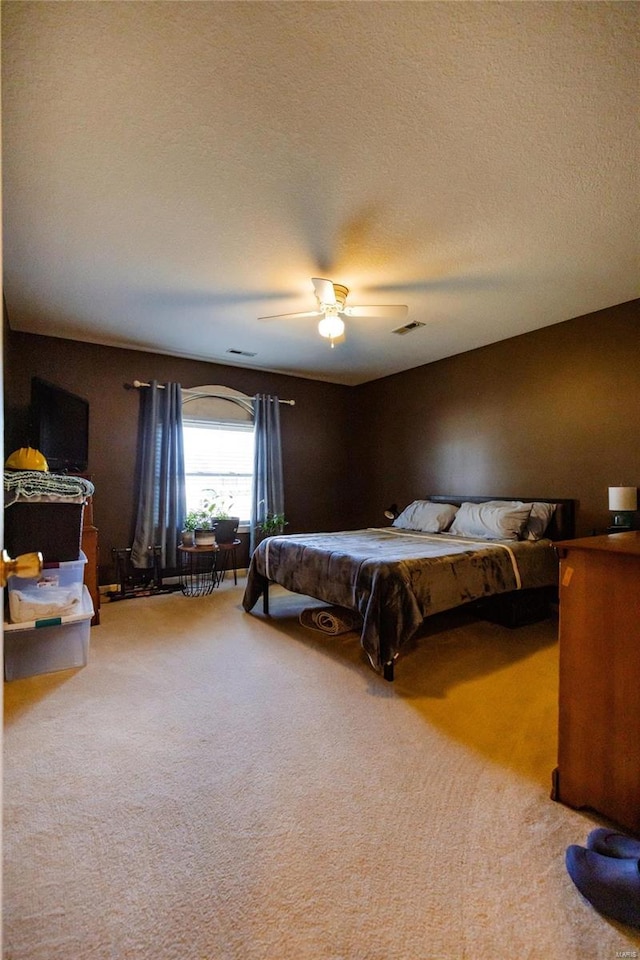 bedroom featuring carpet flooring, a ceiling fan, visible vents, and a textured ceiling